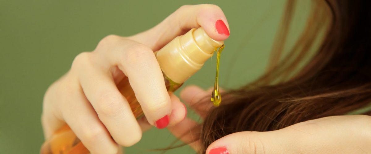 Woman applying oil on hair ends, split hair tips, dry hair or su