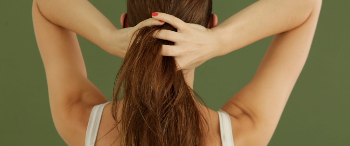 Studio shot of woman applying hair oil with her fingers