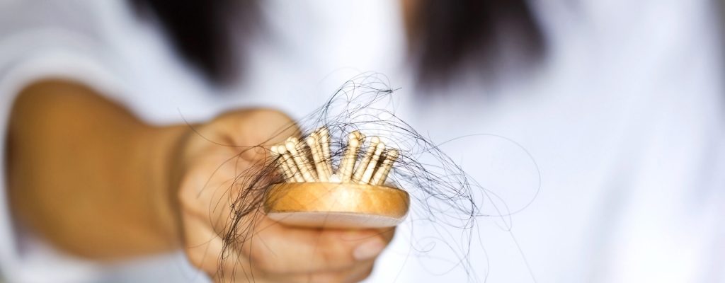 woman losing hair on hairbrush in hand, soft focus