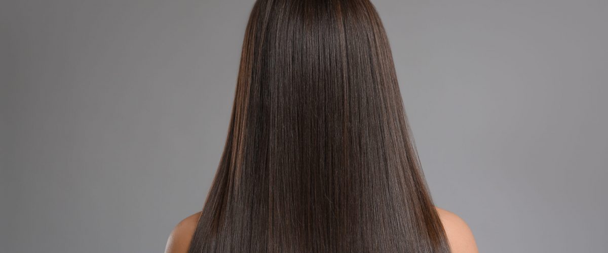 Young woman with beautiful straight hair on grey background